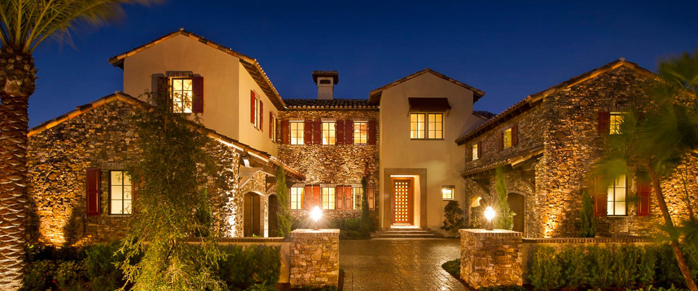 natural brown brick sided home with wide, long driveway and palm trees